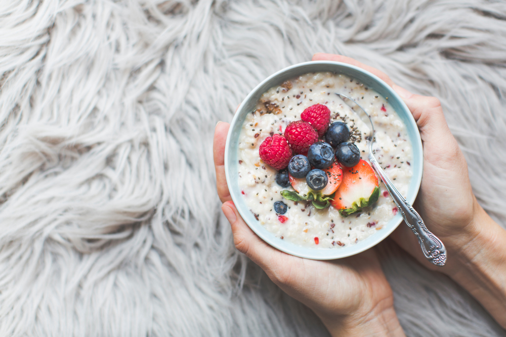 Bowl with porridge in hands on a fur background